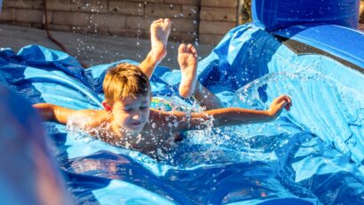 boy sliding down water slide on stomach.