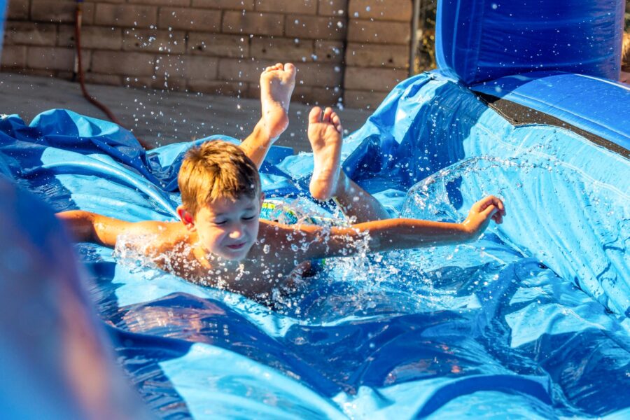 boy sliding down water slide on stomach.