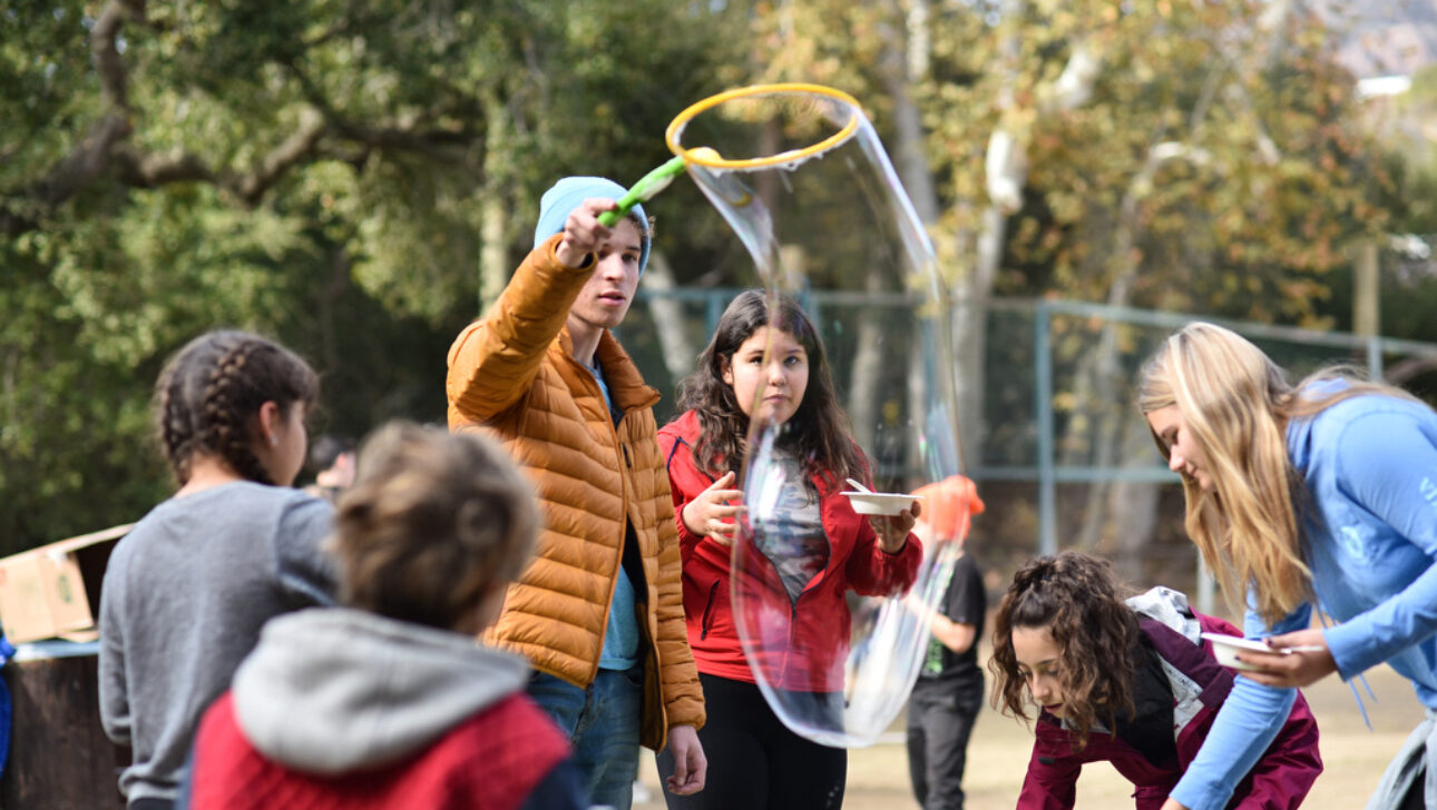 kids making large bubbles outside.