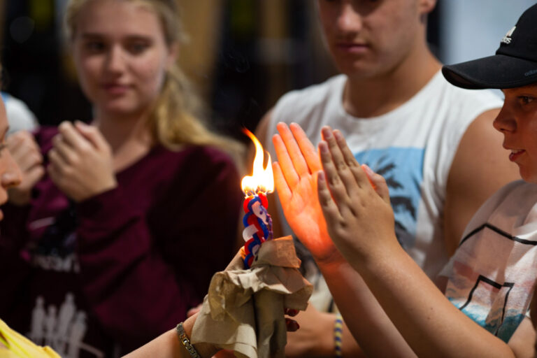 teens holding hands near a candle.