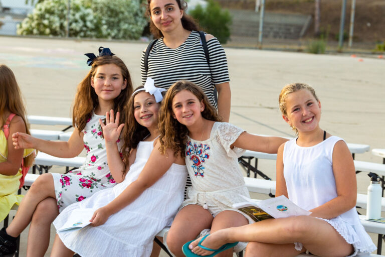 group of girls smiling on a bench.