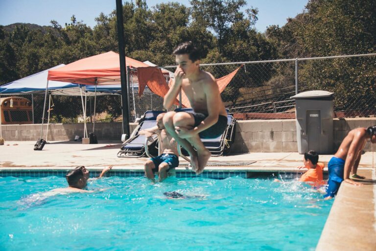 boy mid air jumping into a pool.