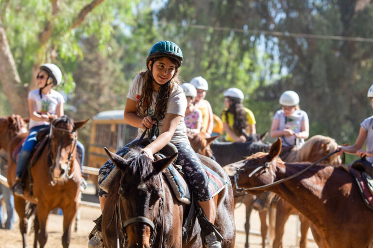 girl petting the horse shes riding.