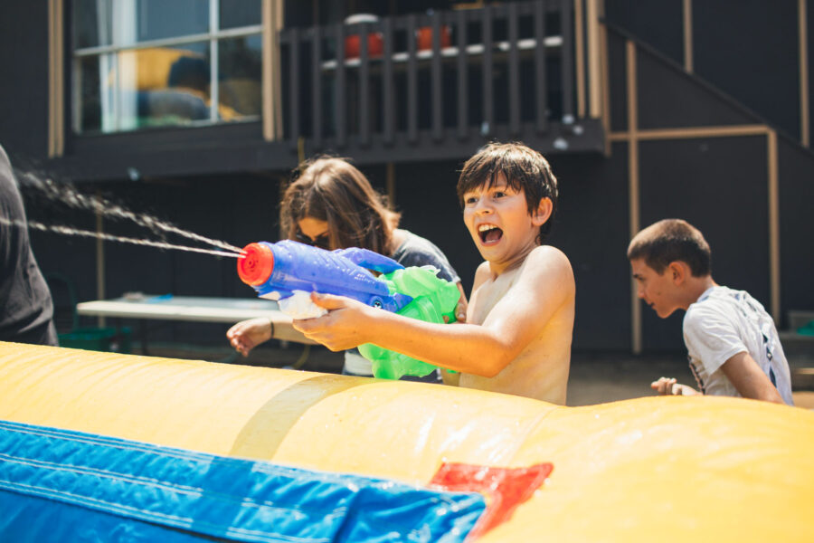 boy firing a super soaker behind an inflatable slide.