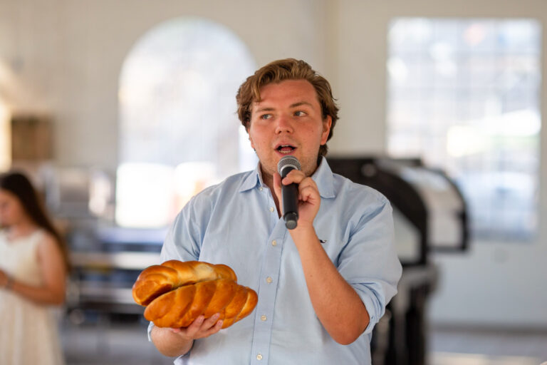 teen boy talking with two loaves of bread in his hand.