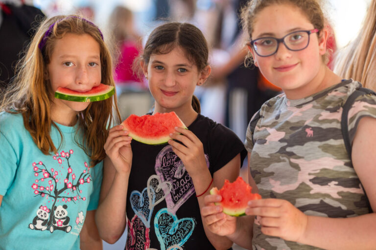 three girls eating watermelon.
