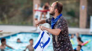 man waving an israeli flag next to a swimming pool.