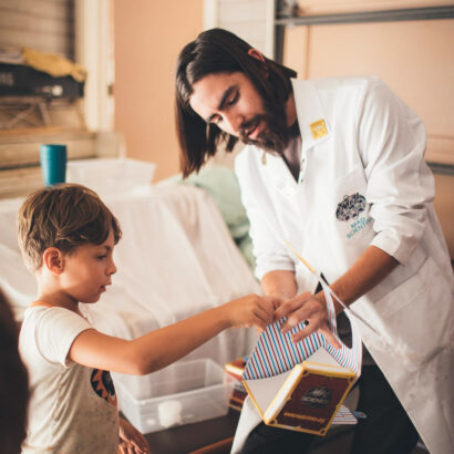 man in a white lab coat showing something to a boy.
